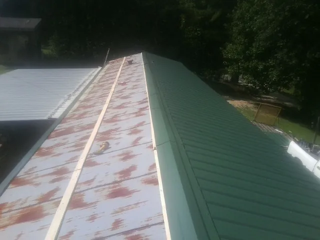 Old rusted panels beside newly installed green metal roofing — Wind Damage Roof Repair by Roofing Brothers in Wildwood